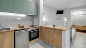 Cocina moderna con armarios de madera, lavavajillas, horno y encimera con frutero.