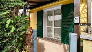 A house with a green door, a window, and a security device on the wall. - Villa 'Pairola' with Sea View, Private Garden and Air Conditioning (San Bartolomeo al Mare)
