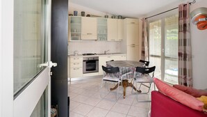 A kitchen with a dining table, chairs, and a red sofa. - Villa 'Pairola' with Sea View, Private Garden and Air Conditioning (San Bartolomeo al Mare)