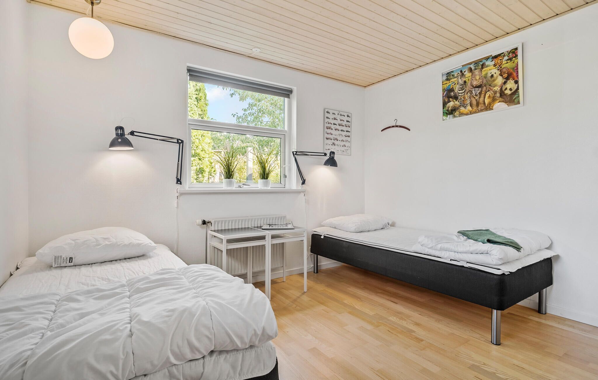 Une chambre avec deux lits, une fenêtre, un radiateur et un bureau.
