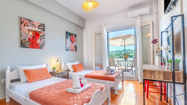 Camera d'albergo con due letti, una scrivania, una sedia e un balcone con vista.