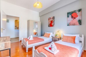 A hotel room with two single beds, a wooden table, a mirror, and artwork on the walls. - Apartment 'Maestro' with Shared Terrace, Wi-Fi and Air Conditioning (Paxos)