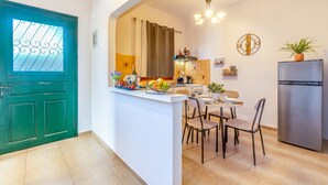 Una cucina con zona pranzo, una porta verde e un frigorifero.