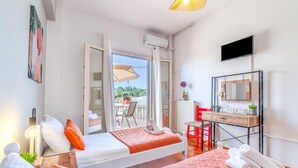 Una camera d'albergo con due letti, una scrivania, una televisione e un balcone con una sedia.