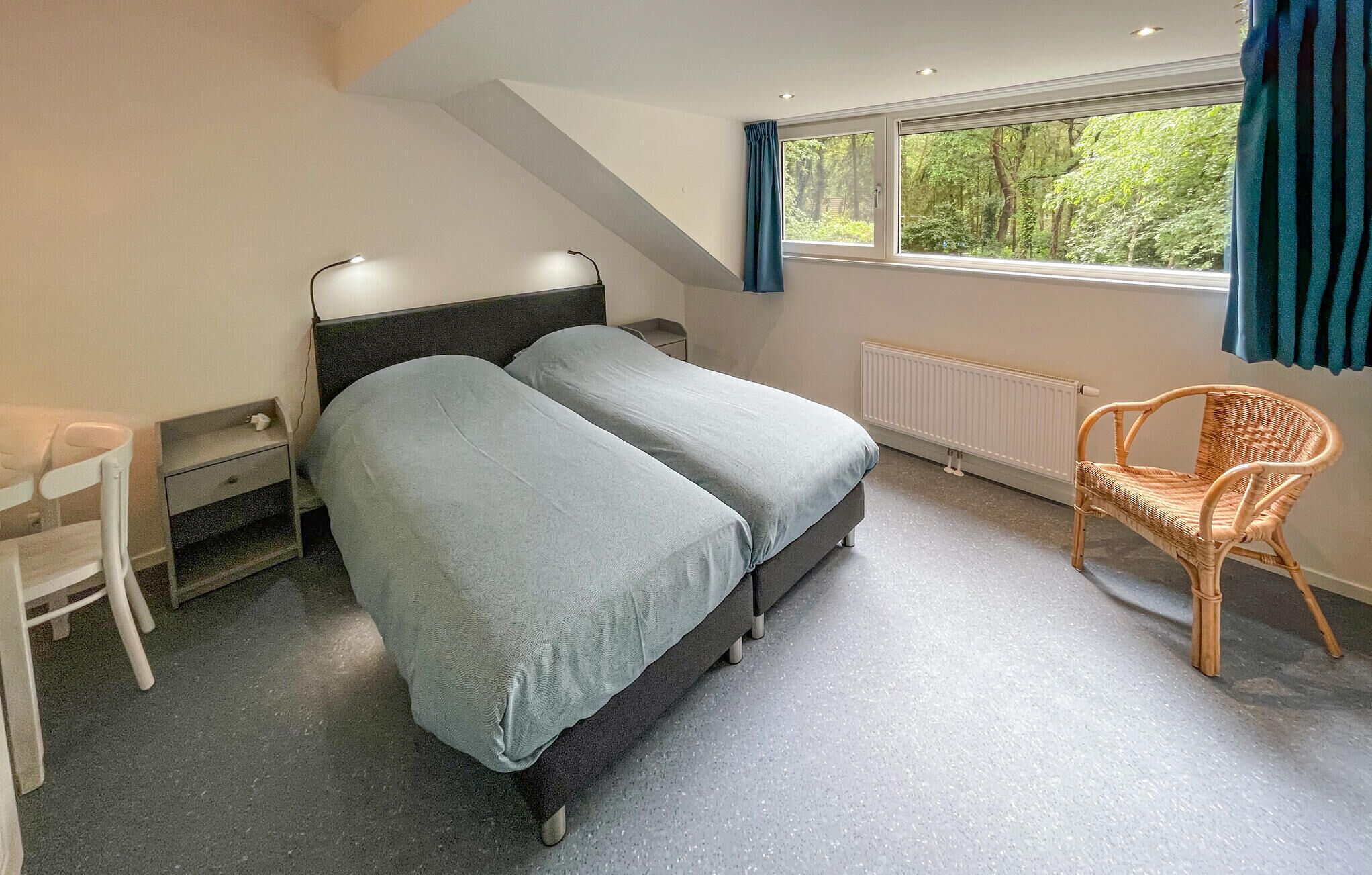 A bedroom with a bed, a chair, a desk, and a window with curtains.