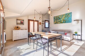 A modern kitchen with a dining table, chairs, and pendant lighting. - Non dire Gatto – Elegant Rooftop Apartment in Alghero (Alghero)