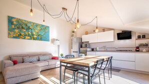 Eine moderne Küche mit weißen Schränken, einem Holzespeisetisch und einem flachbildfernseher, der darüber angebracht ist.