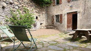 Un bâtiment en pierre, à l’aspect rustique, avec une porte en bois et un mur de pierres.