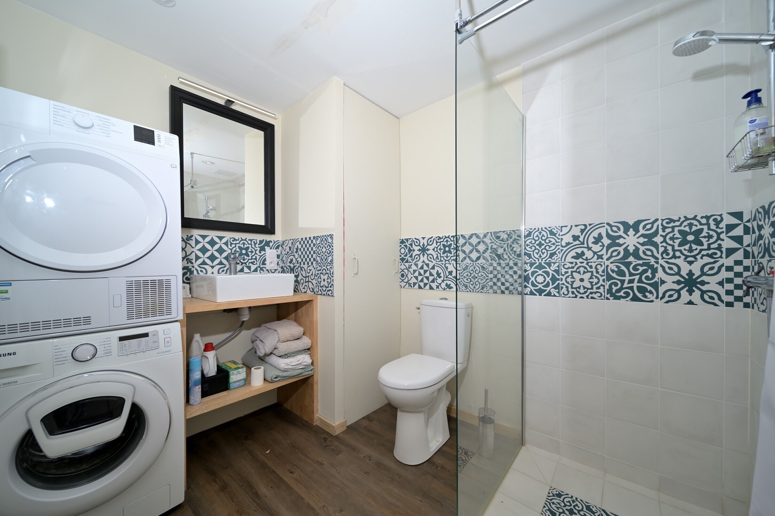 Een badkamer met een wasmachine, toilet en betegelde vloer.