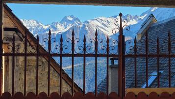 A mountain view through a metal fence with a wooden building in the foreground.