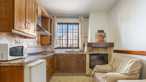 Una cocina con armarios de madera, microondas, fregadero y chimenea.