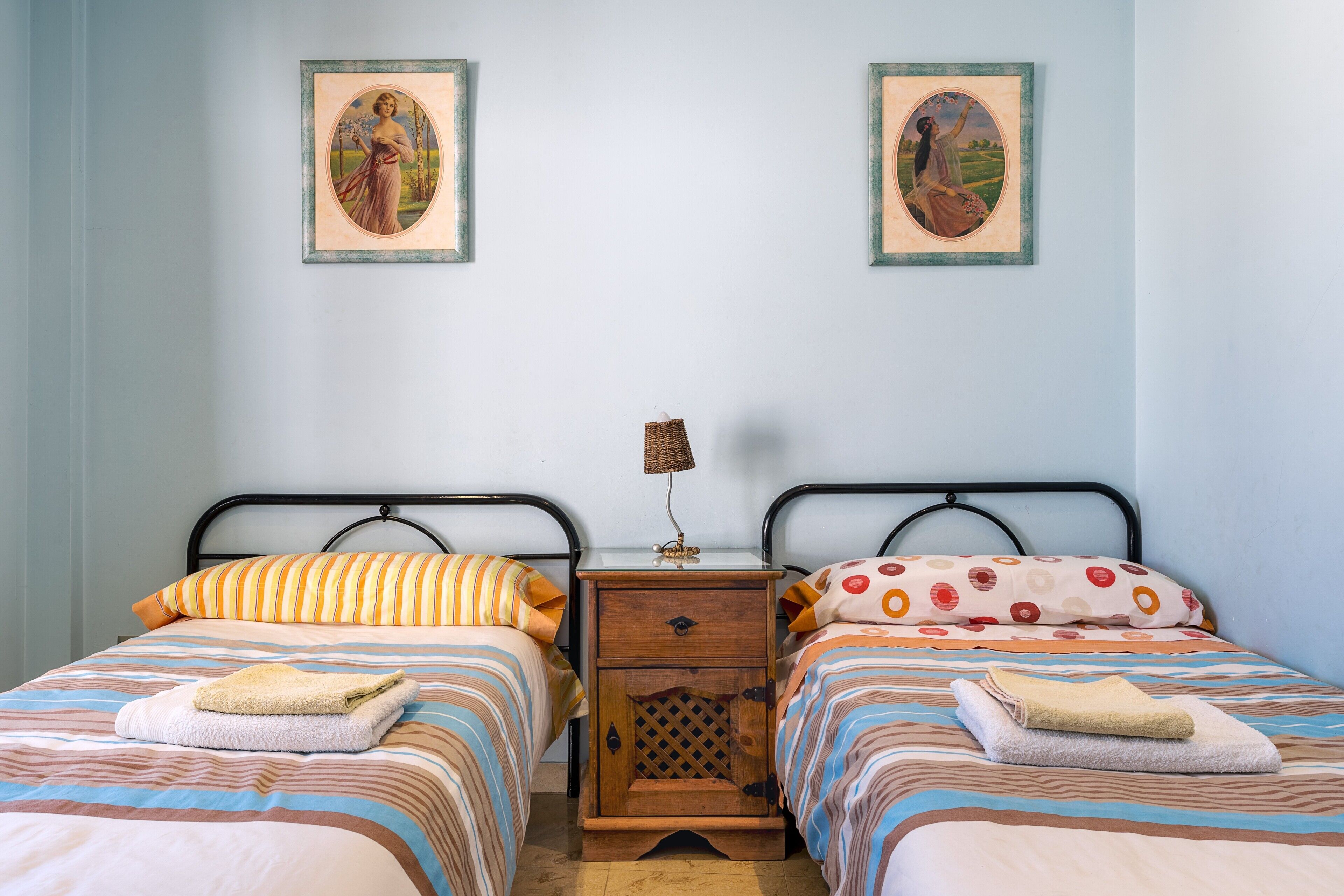 Un lit double avec une literie à rayures et une table de chevet avec une lampe.