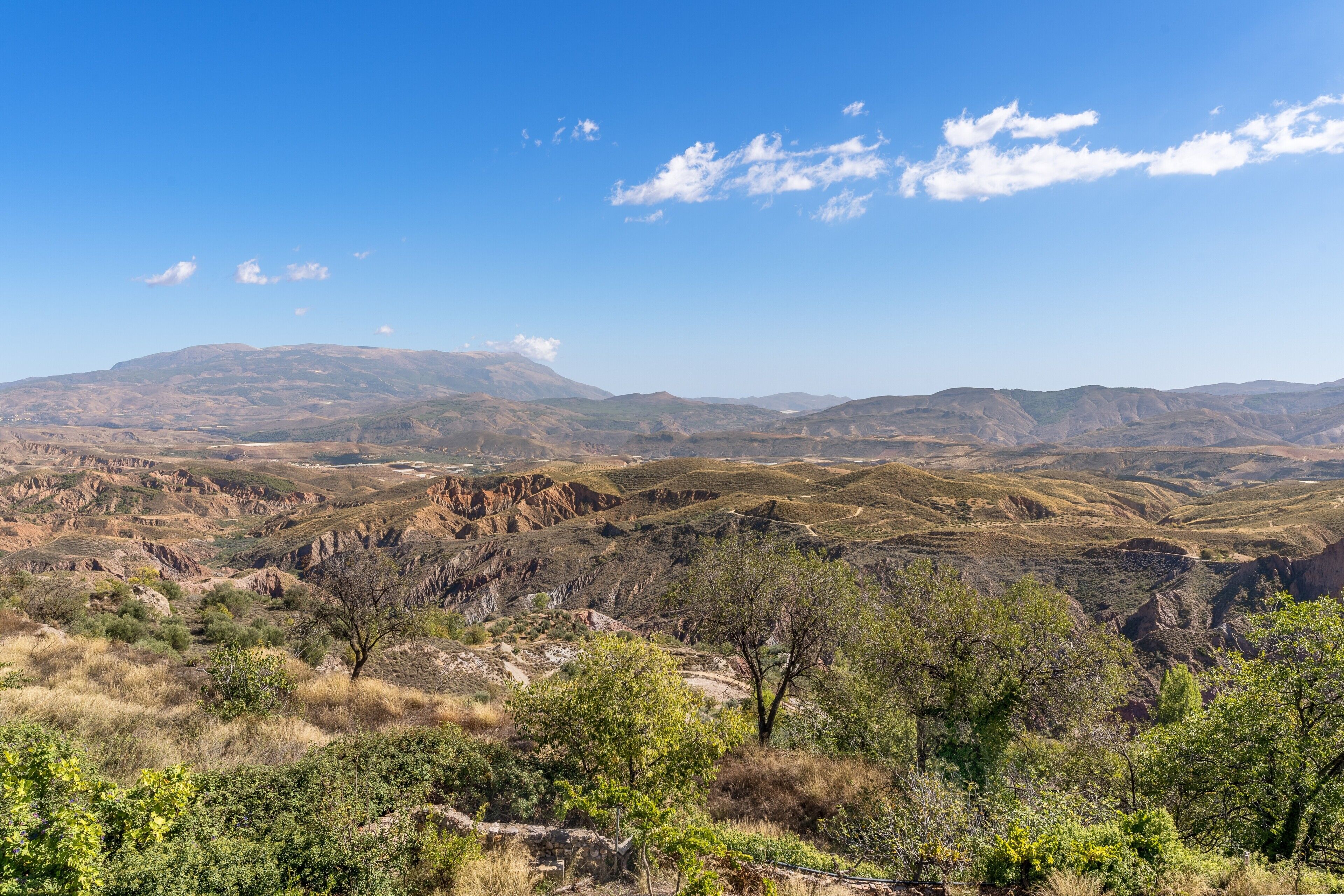 Un paysage montagneux à la végétation clairsemée, sous un ciel dégagé.