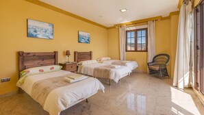 Habitación de hotel con dos camas, una ventana con cortinas, una silla y dos cuadros en la pared.