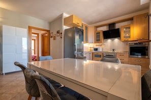Une cuisine moderne dotée d’un îlot central, de meubles en bois, d’appareils électroménagers en acier inoxydable et d’un coin repas avec des chaises.