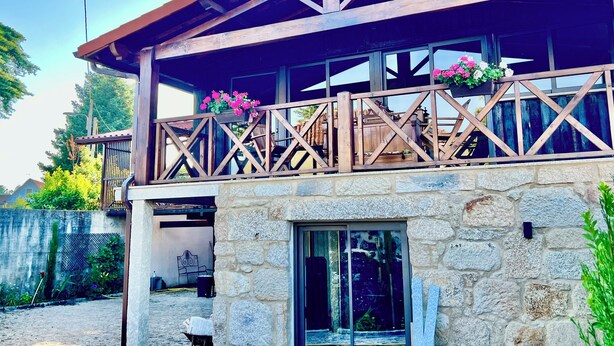 Un bâtiment en pierre doté d’un balcon en bois et d’un porche abrité.