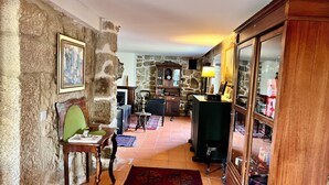 Une pièce aux murs de pierre, comprenant une table à manger, des chaises et un tapis à motifs.