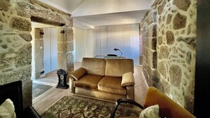 Un salon avec un mur en pierre, un canapé, un tapis à motifs et une horloge.