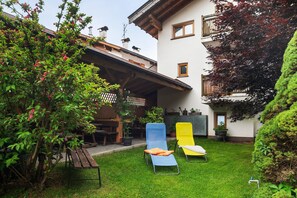 Een terras met twee lounge fauteuils, een houten tafel en een bloempot.