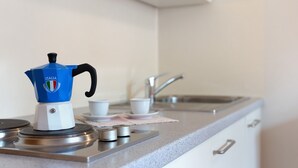 Et køkken med kaffemaskine, kopper og vask.