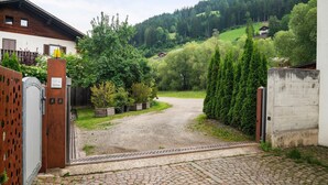 A gravel driveway leading to a house with a wooden fence and greenery. - Apartment 'Appartment Love' with Mountain View, Shared Garden and Wi-Fi (Sarnthein)