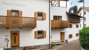 A building with a sign 'frieobeim,' wooden balconies, a stone staircase, and a cobblestone path. - Apartment 'Appartment Love' with Mountain View, Shared Garden and Wi-Fi (Sarnthein)