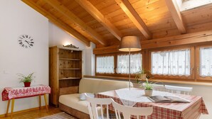 A cozy room with a wooden ceiling, a sofa, a table with a checkered tablecloth, and a bookshelf. - Apartment 'Appartment Love' with Mountain View, Shared Garden and Wi-Fi (Sarnthein)