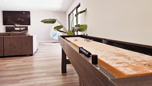 A modern living room with a pool table, a sofa, and a TV. - Seasun Hostel (Northridge)