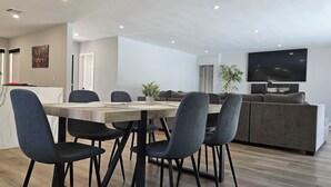 A modern living room with a dining area, a sofa set, a flat-screen TV, and a potted plant. - Seasun Hostel (Northridge)