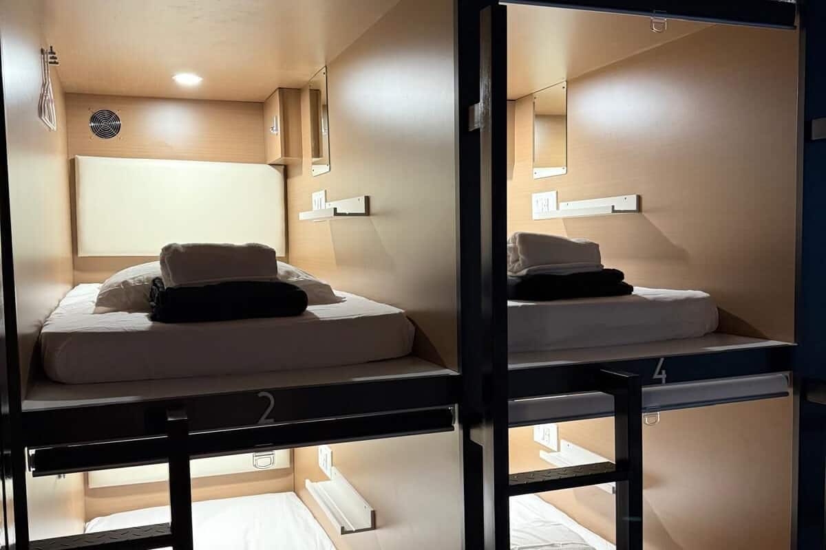 A room with bunk beds, each labeled with a number, and a small window with a view of the outside.