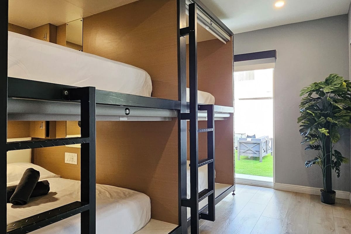 A room with bunk beds, a potted plant, and a view of the outdoors.