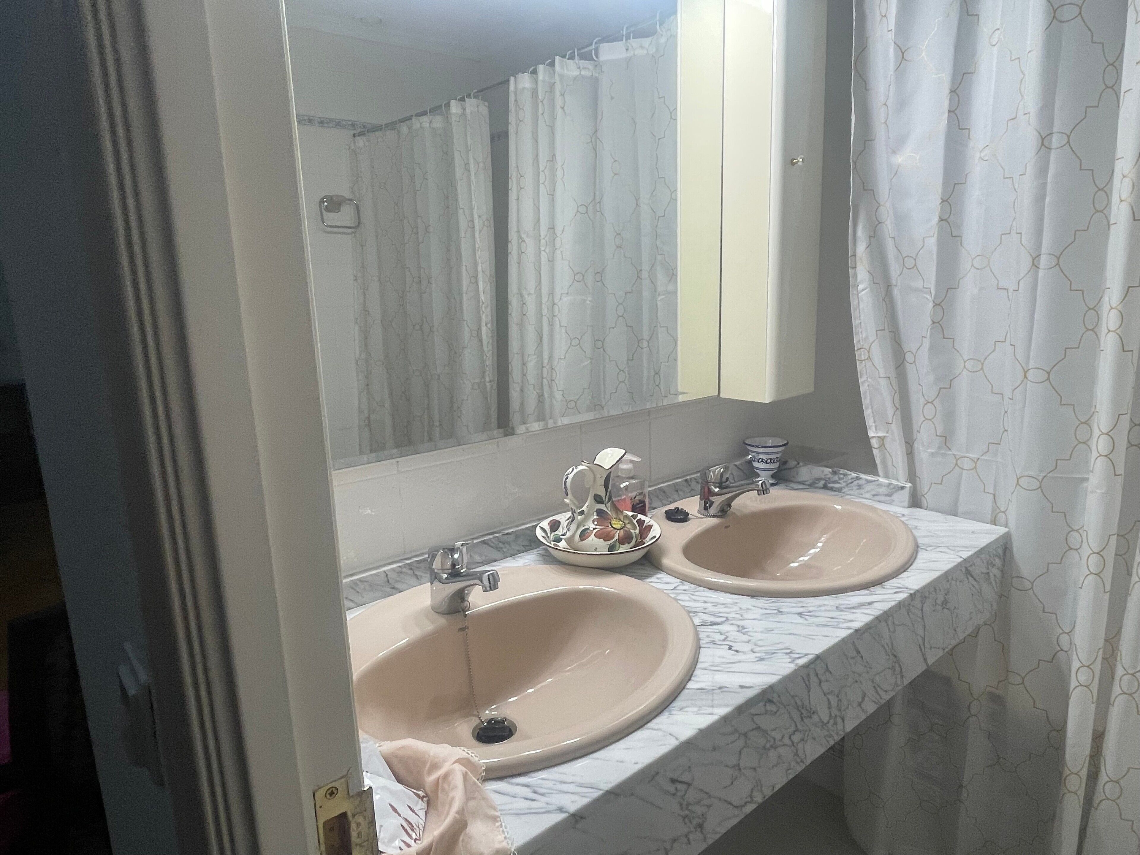 Un baño con dos lavamanos, un espejo y una cortina de ducha.