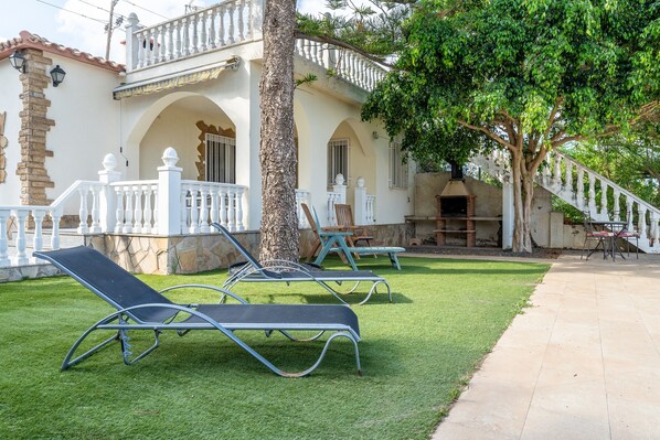 A villa with a white balcony, a tree, and a paved patio area. - Holiday Home 'Can Manya' with Private Pool, Private Terrace and Private Garden (Alcanar)