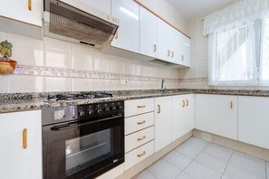 A kitchen with white cabinets, a black stove, and a tiled backsplash. - Holiday Home 'Can Manya' with Private Pool, Private Terrace and Private Garden (Alcanar)