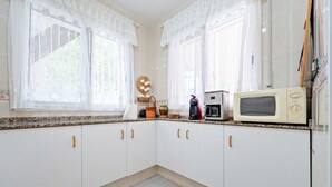 Eine Küche mit weißen Schränken, einer Mikrowelle und einer Kaffeemaschine auf der Arbeitsfläche.