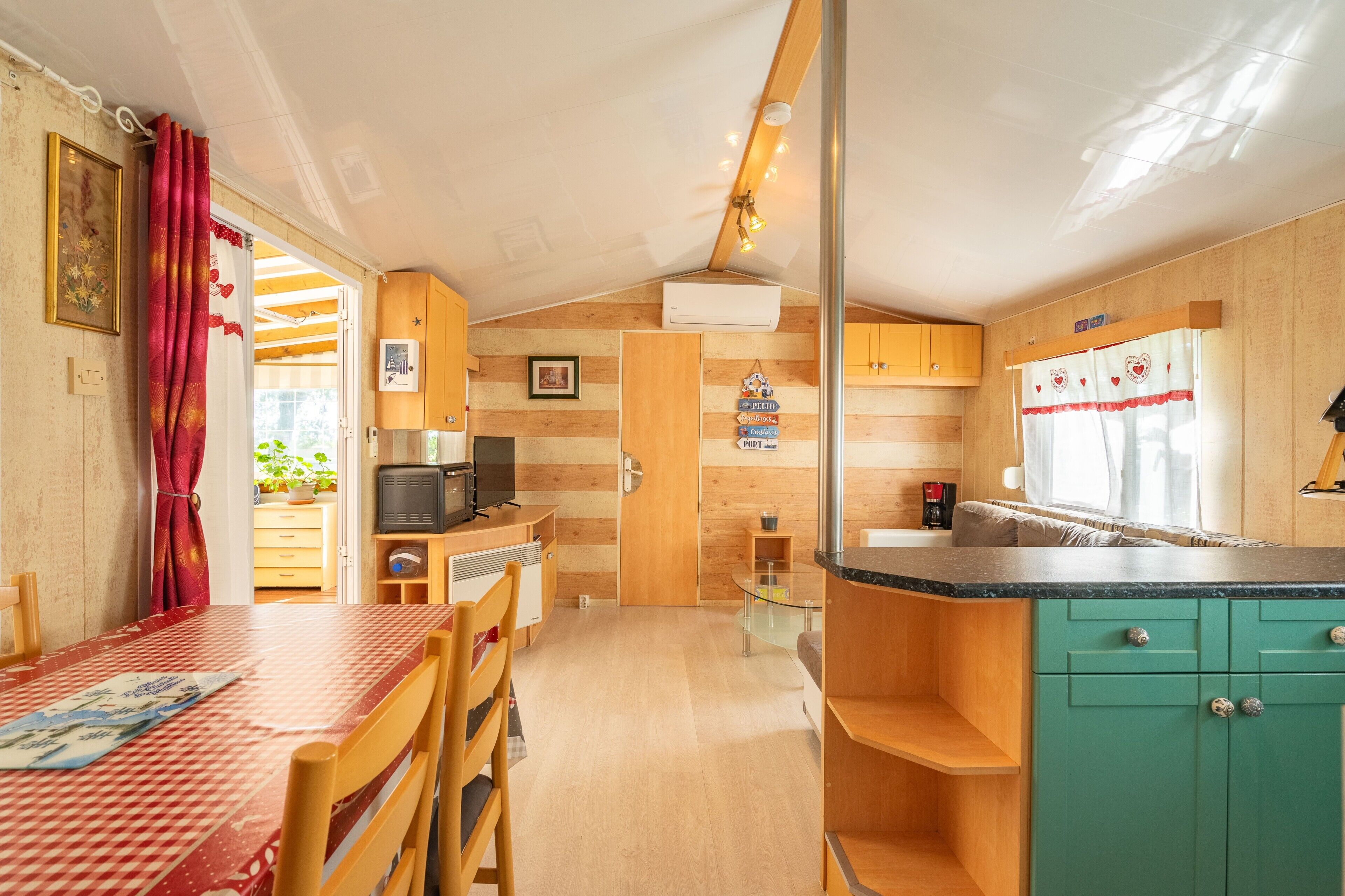 A compact kitchen with wooden cabinets, a dining table, and a small TV.