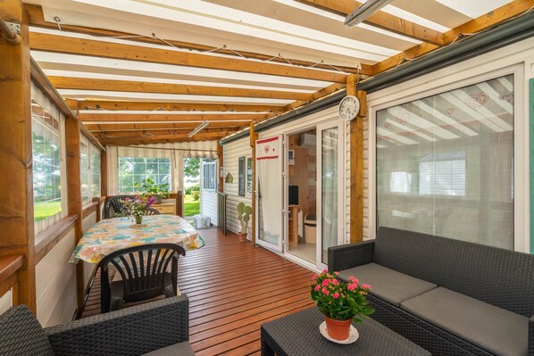 Un patio couvert avec une table et des chaises, un canapé en osier et une plante en pot.
