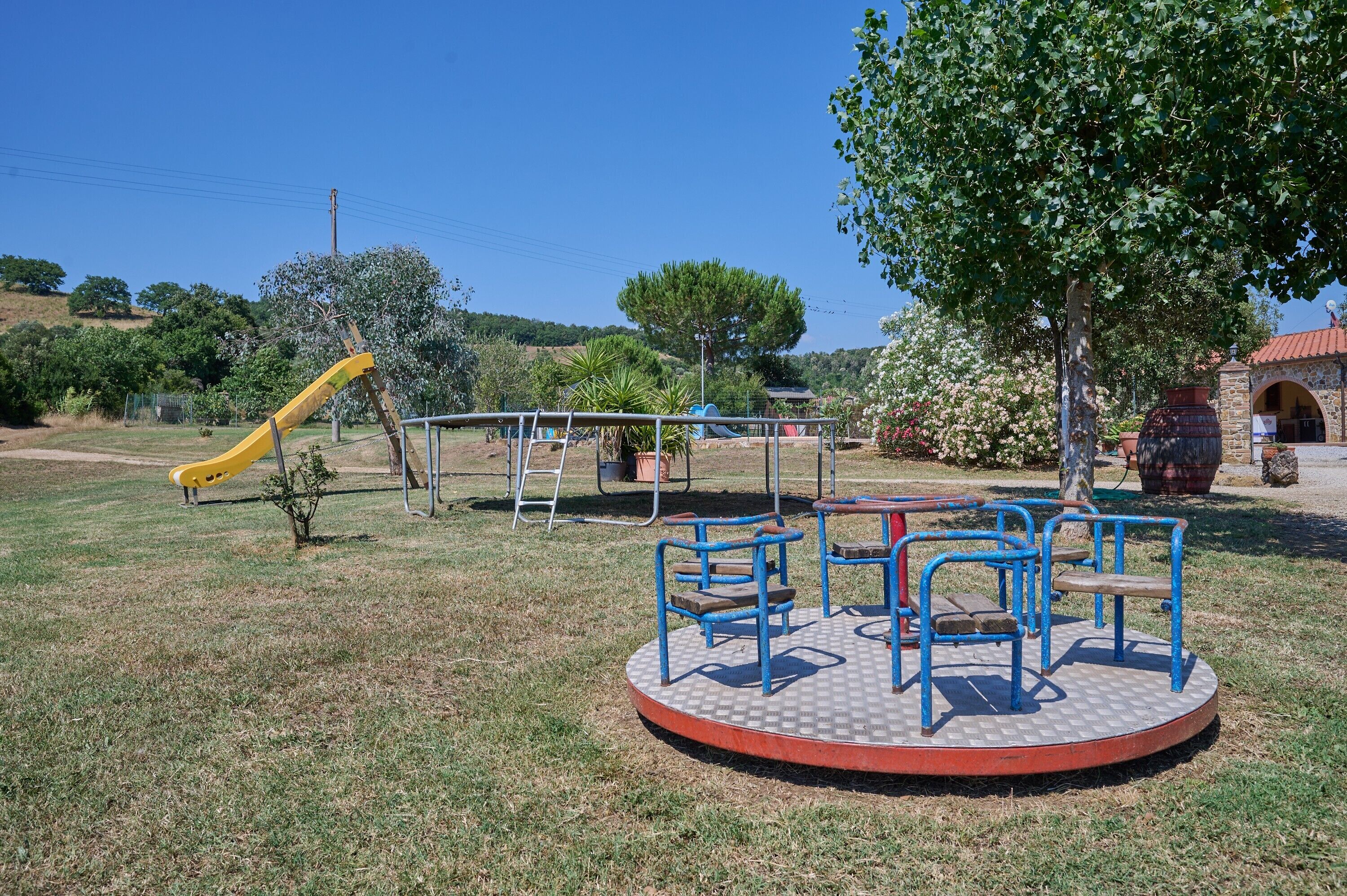 Une aire de jeux avec un toboggan, des balançoires et un espace de repos circulaire.