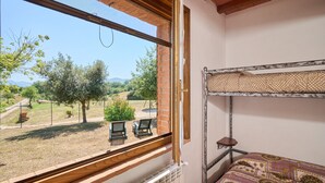 Ein Zimmer mit Etagenbett, einem Fenster mit Gartenblick und einem kleinen Tisch mit einer Pflanze.