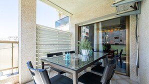 A balcony with a glass table and chairs, a potted plant, and a view of the city. - Apartment 'Bumbai' with Shared Pool, Private Garden and Air Conditioning (Creixell)