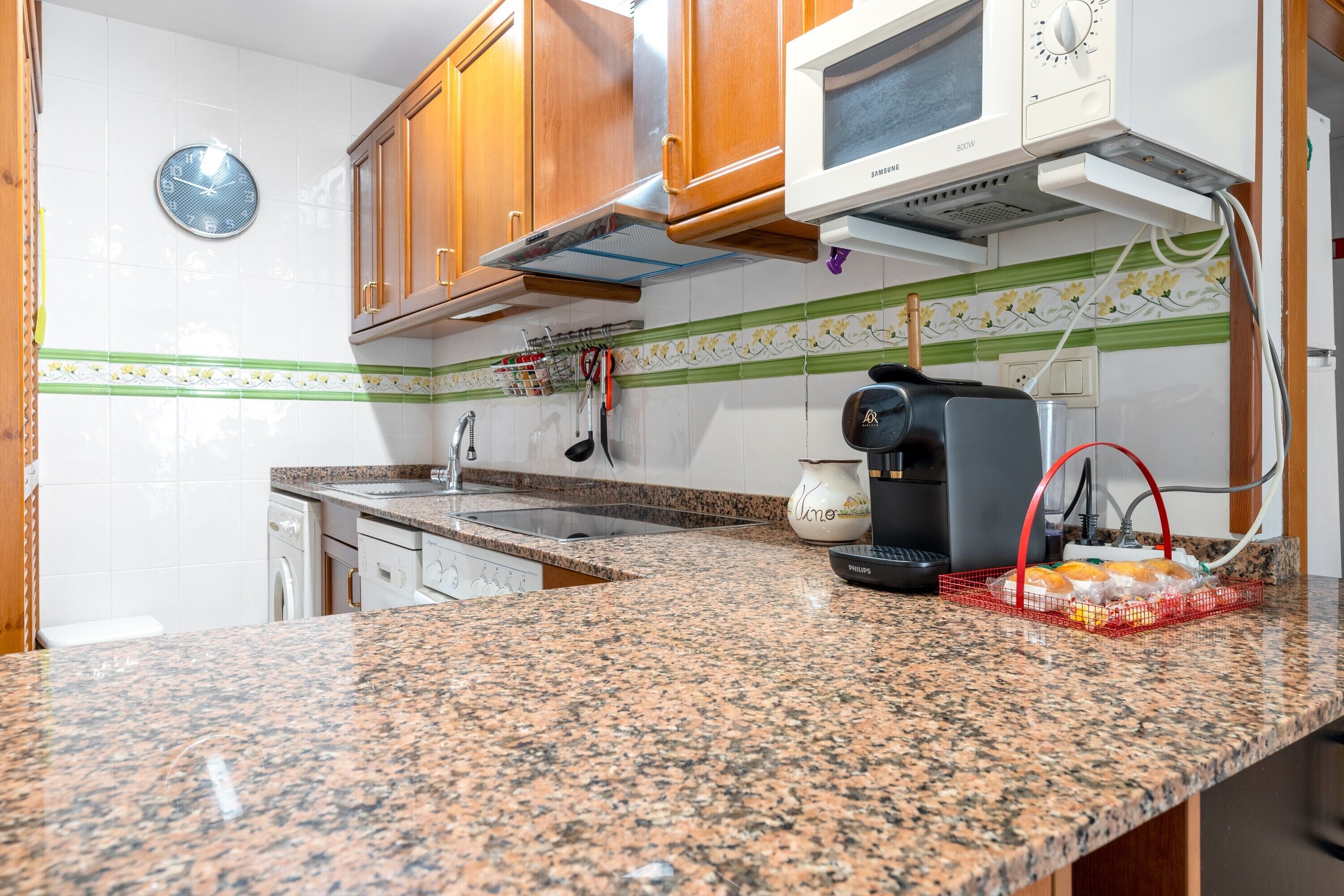 A kitchen with granite countertops, wooden cabinets, a microwave, and a coffee maker.