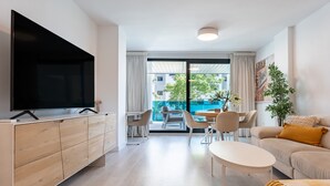 A modern living room with a TV, sofa, coffee table, and a balcony with a view. - Apartment 'Jardines De Las Lagunas' with Mountain View, Wi-Fi and Air Conditioning (Las Lagunas de Mijas)