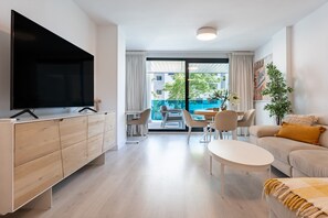 Un salon moderne avec un téléviseur, un canapé, une table basse et un balcon offrant une vue agréable.