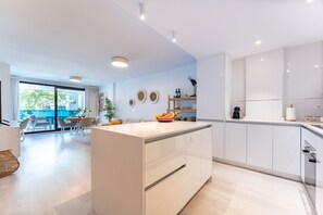 Une cuisine moderne avec des meubles blancs, un îlot central et un coin repas offrant une vue agréable.