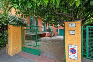 A gated entrance with a no parking sign, a building with a yellow wall, and a green gate.