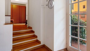 A staircase leading to a room with a clock on the wall and a window with a view of buildings outside.