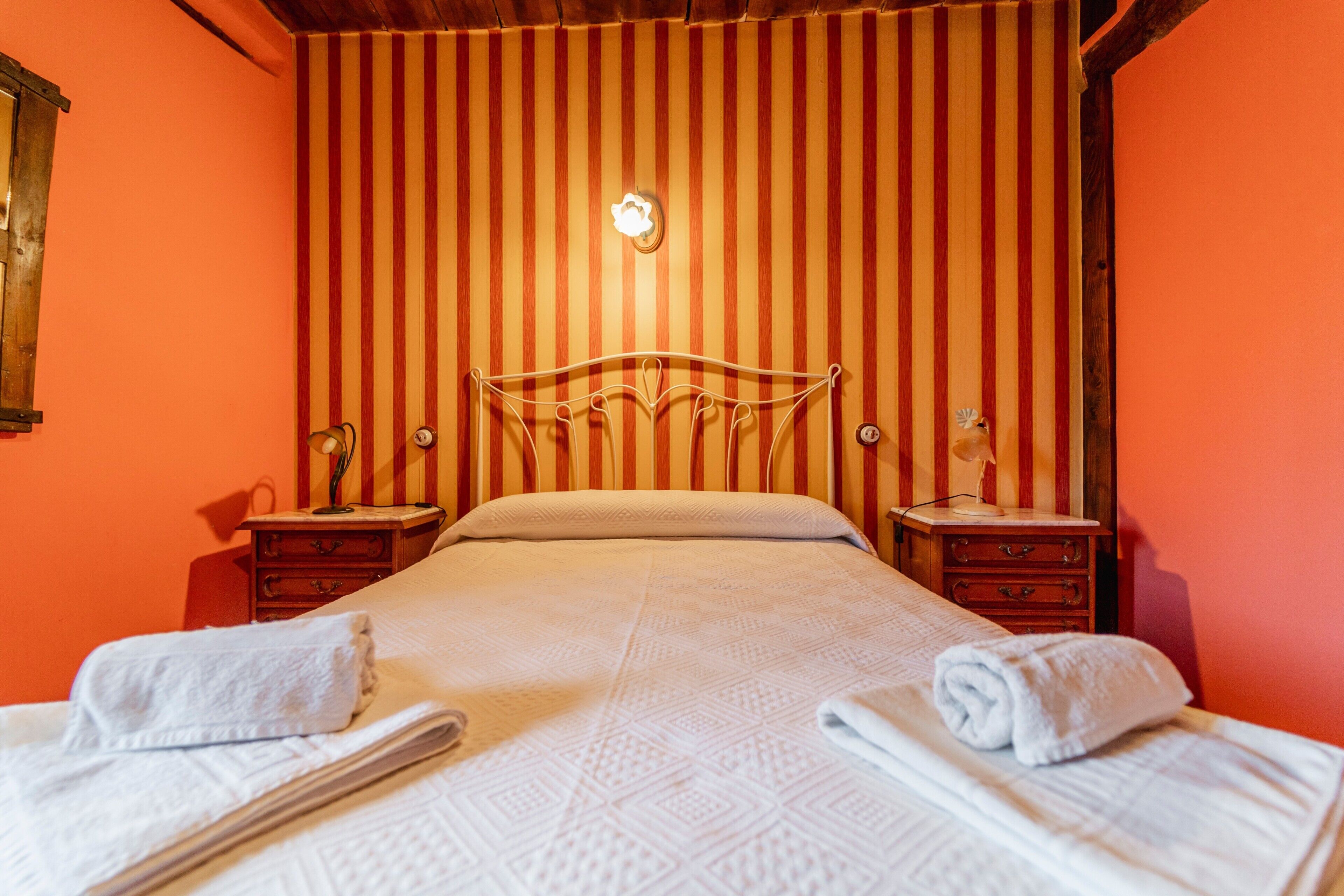A hotel room with a bed, two bedside tables, and a striped wall.