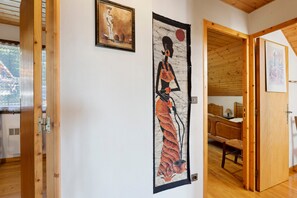 A hallway with wooden flooring, a bed with a wooden headboard, and a door leading to another room. - Chalet 'St Victoire Pied des pistes' with Mountain View, Shared Pool and Wi-Fi (Les Orres)