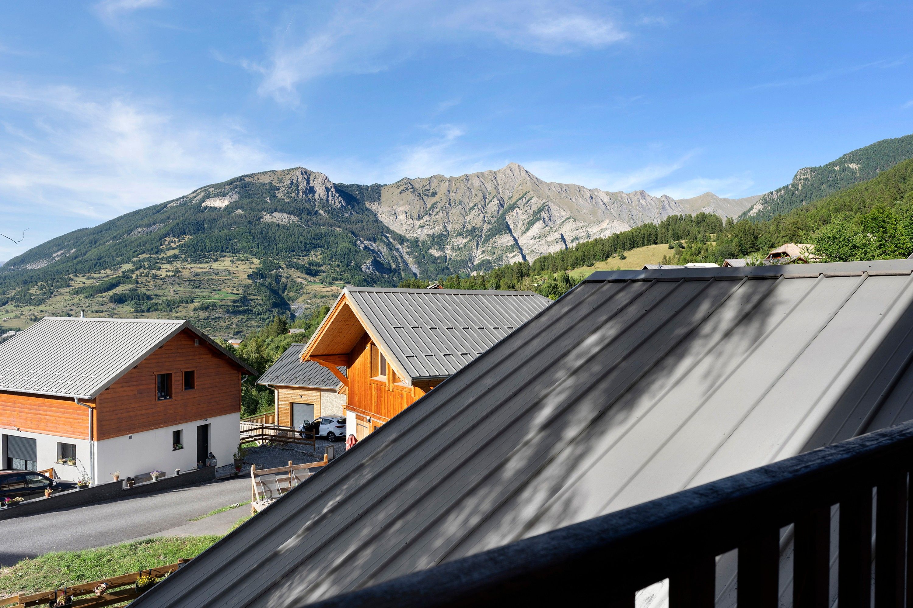 Un paysage de montagne avec un chalet en bois et une voiture garée devant.
