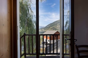 Un balcón de madera con vistas a un paisaje montañoso y un edificio en la parte baja.